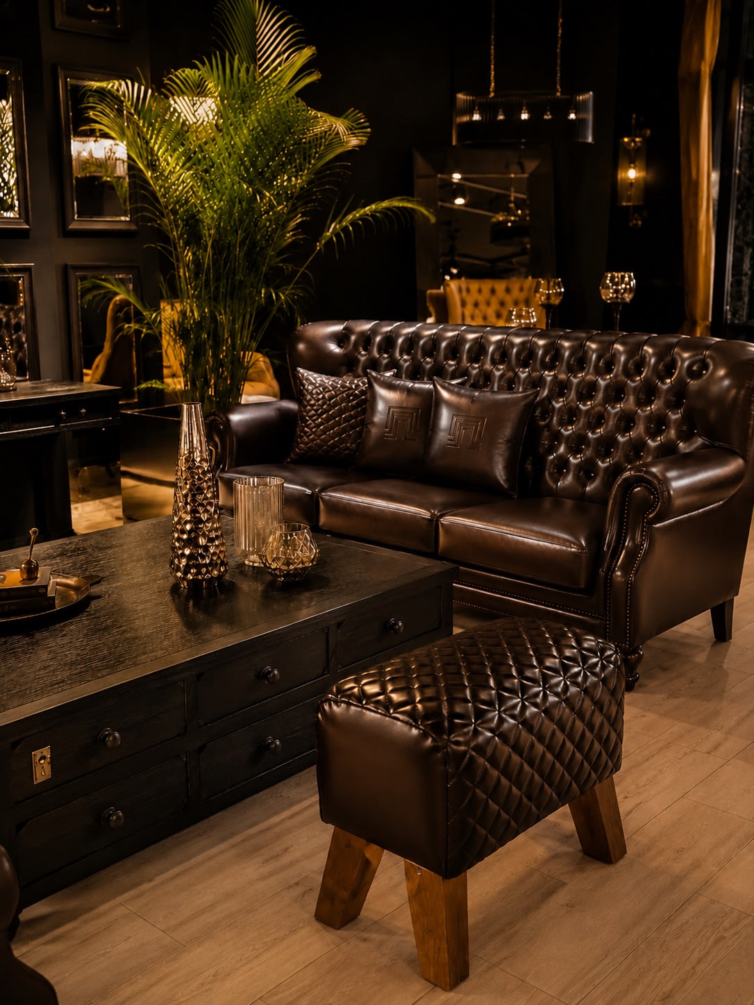 Brown leather Chesterfield sofa with tufted ottoman and dark wood coffee table in the Quadrangle showroom